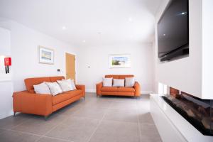 a living room with two orange couches and a tv at Sea Breeze in Portstewart