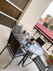 a glass table and two chairs on a balcony at Larnaca Beach Apartment in Larnaca