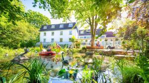 a garden in front of a white house with a pond at Gartenhotel Fettehenne in Erkrath