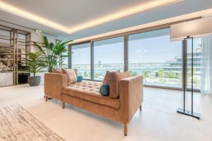 a living room with a couch and large windows at Palm Jumeirah Luxury Apartments by Propr in Dubai