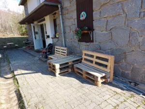 two wooden benches sitting outside of a stone building at Chata Jamy in Vysoke Tatry - Tatranska Lomnica.
