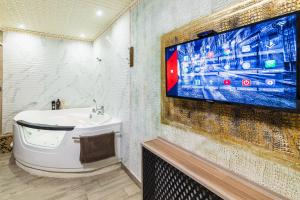 ein Bad mit einem Waschbecken und einem TV an der Wand in der Unterkunft Смарт Апартаменты джакузи in Dnipro