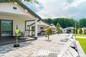 a patio with white chairs and tables and trees at Duet Domki in Jarosławiec