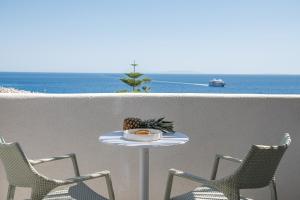 einen Tisch und Stühle auf einem Balkon mit Meerblick in der Unterkunft The Authentic Village Boutique Hotel in Chora Sfakion