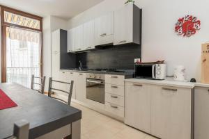 La cuisine est équipée de placards blancs et d'un four avec plaques de cuisson. dans l'établissement Appartamento Madeleine, à Riva del Garda