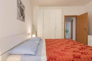 - une chambre avec un lit et une couverture rouge dans l'établissement Appartamento Madeleine, à Riva del Garda