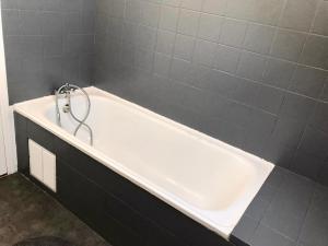 エペルネーにあるAU PETIT BONHEURの灰色のタイル張りの浴室にある白い浴槽