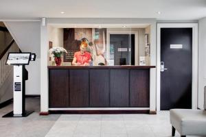 a man standing behind a bar in a lobby at Fortune Huddersfield; Sure Hotel Collection by Best Western in Huddersfield