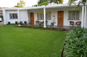 una casa blanca con césped delante en Franka Guesthouse, en Rustenburg