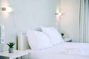 a white bed with white pillows on top of it at Evangelia's Family House in Ormos Panagias