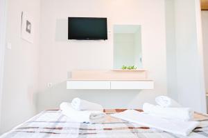 a white room with a bed with towels and a tv at Evangelia's Family House in Ormos Panagias