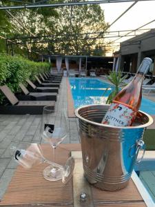 a bottle of wine in a bucket next to wine glasses at Player's Pool&Rooms in Vonyarcvashegy