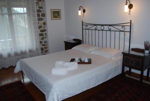 1 dormitorio con 1 cama con sábanas blancas y toallas en Dryades Guesthouse, en Ano Chora