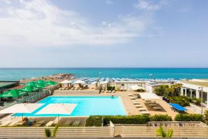 een zwembad met parasols en het strand bij Hotel Stella Marina in Marina di Cecina