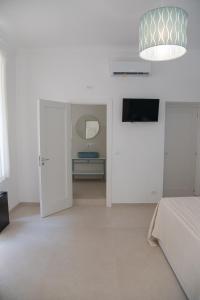 a white bedroom with a bed and a mirror at Casa Thuja in Syracuse