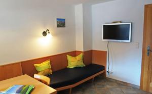 a room with a bench with yellow pillows and a tv at Ferienwohnung Brunnerlehen in Berchtesgaden