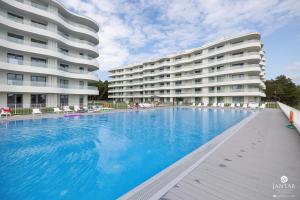 a large swimming pool in front of a building at Jantar Apartamenty - Pearl Apartments Rogowo in Rogowo
