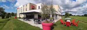 um edifício com cadeiras vermelhas e mesas em frente em ibis Les Herbiers em Les Herbiers