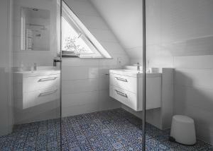 a white bathroom with a sink and a shower at Brzozowy Zaułek in Bydlino