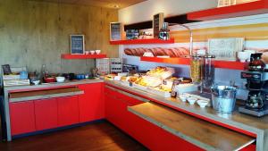 une cuisine avec des placards rouges et un comptoir avec de la nourriture dans l'établissement ibis Les Herbiers, aux Herbiers