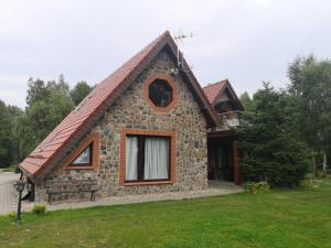 una pequeña casa de piedra con techo rojo en Brzozowy Zaułek en Bydlino