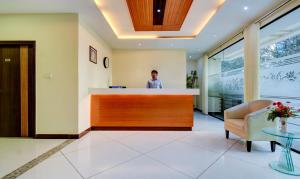 a man standing at a counter in a hospital lobby at Treebo Trend Primeland Suites in Bangalore