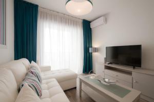 een woonkamer met een witte bank en een flatscreen-tv bij INFANTAS in Granada