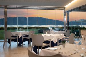 a restaurant with white tables and chairs and windows at Hotel Corte Rosada in Porto Conte
