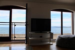 a living room with a flat screen tv and windows at Beachfront Panoramic Seaview Free Wifi & Parking in Lossiemouth