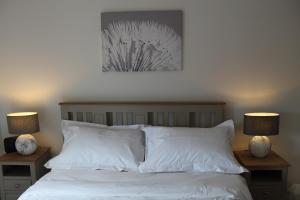 a bedroom with a bed with white sheets and two lamps at Beachfront Panoramic Seaview Free Wifi & Parking in Lossiemouth