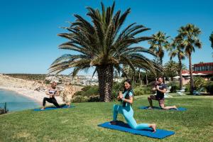 a group of people doing yoga on the grass near the beach at Boutique Hotel Vivenda Miranda in Lagos