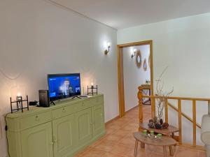 a living room with a television on a green cabinet at Thermal River Apartment in Furnas
