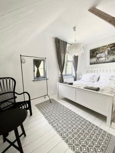 une chambre blanche avec un lit et une chaise dans l'établissement Spokój mi daj, à Sorkwity