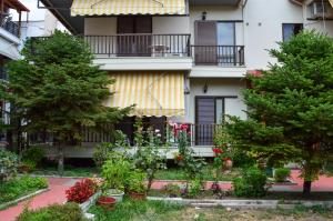 un jardin en face d'un bâtiment planté d'arbres et de fleurs dans l'établissement Manos Kritikakis Apartments, à Platamonas