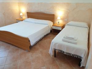 a bedroom with two beds and two tables with lamps at Agriturismo Baratz in Santa Maria la Palma