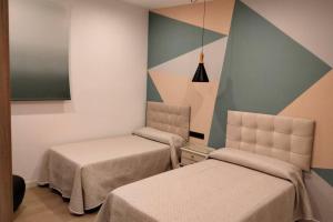 a room with two beds and a painting on the wall at Alojamiento Rural La Viña del Cerezo in Huelma +15 photos