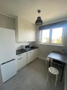 a kitchen with white cabinets and a table and a window at SZPITAL ZDROJE Apartment in Szczecin