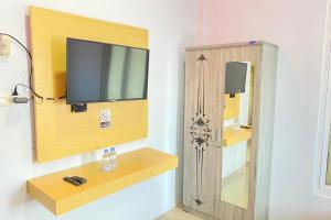 une pièce avec une télévision et une armoire en bois dans l'établissement Homestay Syariah Callista Bantaeng Mitra RedDoorz, à Bombong