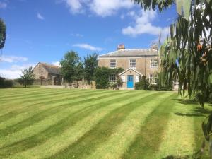 a large grass field in front of a house at Smeaton Farm Luxury B&B in St Mellion