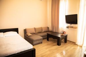 - un salon avec un lit, un canapé et une télévision dans l'établissement Natali, à Tbilissi