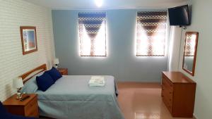Un dormitorio con una cama y dos ventanas. en Apartamento Loft II Select Real Caldas de Reis, en Caldas de Reis