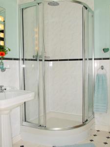 a shower with a glass door next to a sink at Lobhill Farmhouse Bed and Breakfast and Self Catering Accommodation in Okehampton