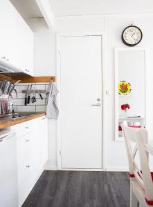 a kitchen with white cabinets and a clock on the wall at Karl-Oskars Krypin in Visby
