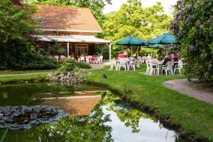 einen Garten mit Tischen, Stühlen und einem Teich in der Unterkunft Gasthof Bathmann in Loxstedt