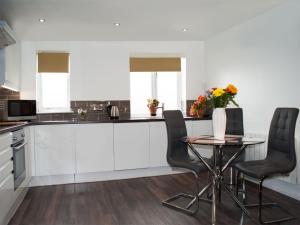 a kitchen with a table and two chairs and a table with a laptop at East Midland House FREE Private Parking Fast WiFi Smart TV with Garden in Kettering