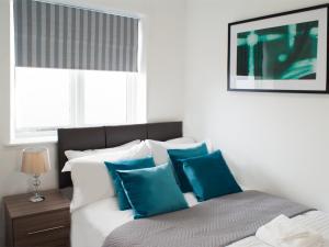 a bedroom with a bed with blue and white pillows at East Midland House FREE Private Parking Fast WiFi Smart TV with Garden in Kettering +3 photos