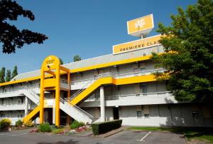 un bâtiment jaune et blanc avec un panneau en haut dans l'établissement Premiere Classe Arles, à Arles