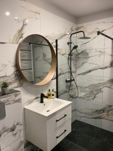 La salle de bains est pourvue d'un lavabo blanc et d'un miroir. dans l'établissement Apartament Luna, à Biała Podlaska