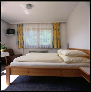 sypialnia z dużym łóżkiem z żółtymi zasłonami w obiekcie Pension Kristall w mieście Bramberg am Wildkogel