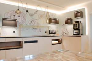 a kitchen with white cabinets and a wall with drawings on it at CMA Stift Ossiach in Ossiach